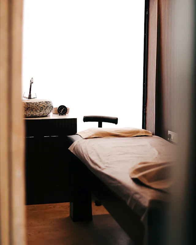 A treatment table made up with a beige sheet beside a bright window