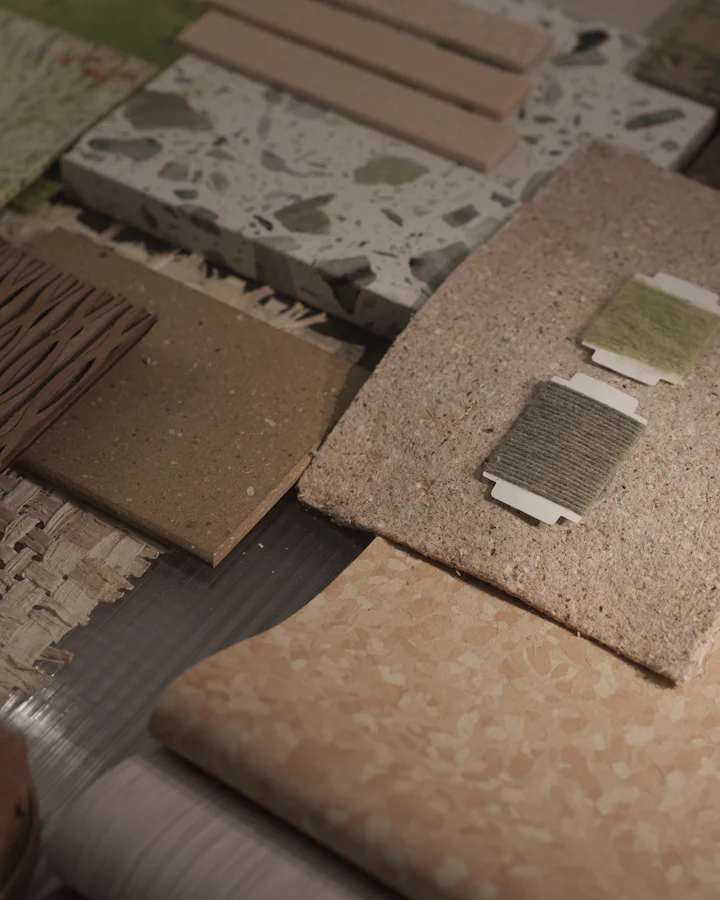 Material samples on a table: terrazzo, clay tile slips, a ribbed timber panel and fibre boards