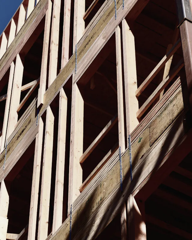 The bare timber frame of a building going up, seen from below against the sky