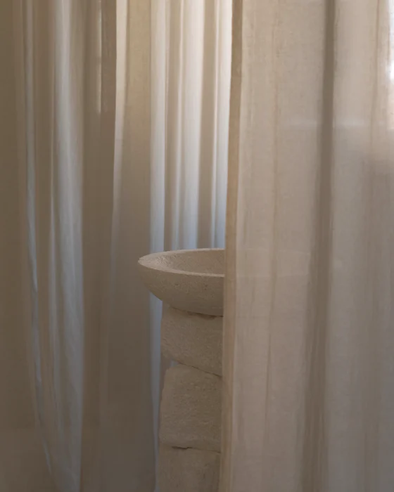 Sheer linen curtains in soft daylight, a white washbasin half hidden behind them
