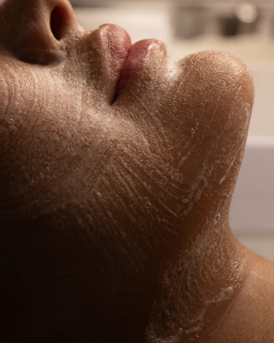A fine cleansing scrub on a client’s cheek, chin and neck, seen from the side