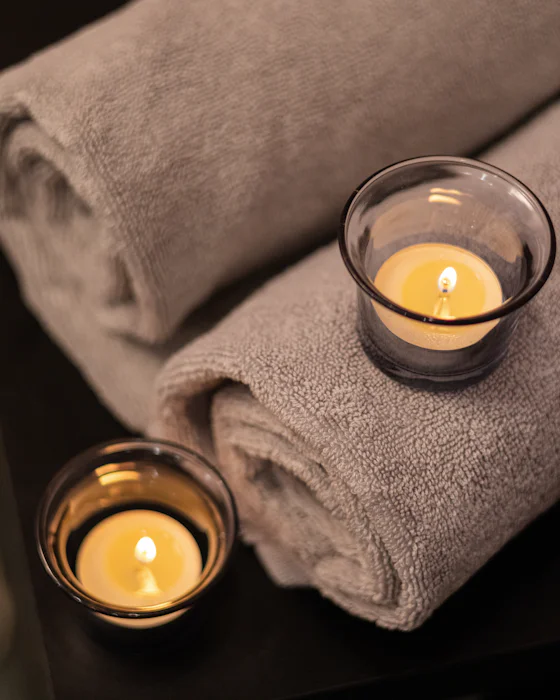 Rolled taupe towels with two lit tealights in glass holders