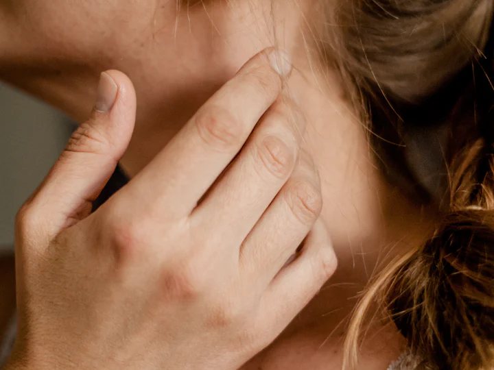 A hand resting along the jaw and neck in soft light