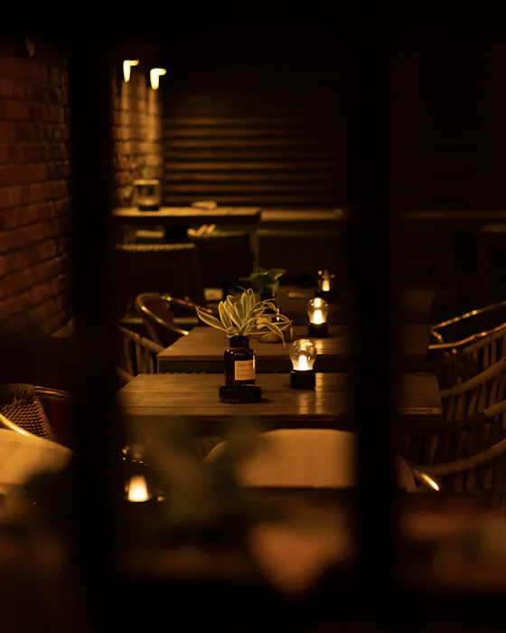 Tables with small lamps in a dark room, seen through a doorway