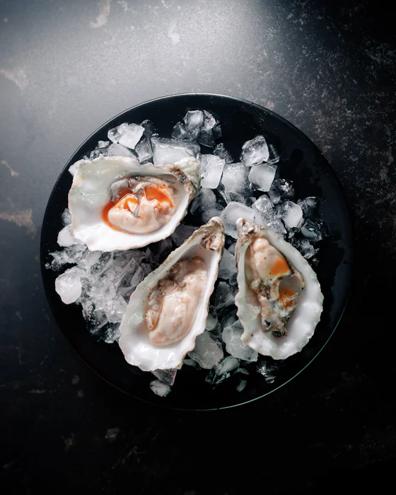 Three oysters on crushed ice on a black plate