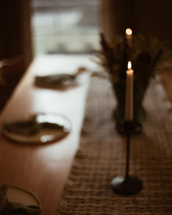 Lit taper candles and dried flowers along a long oak table