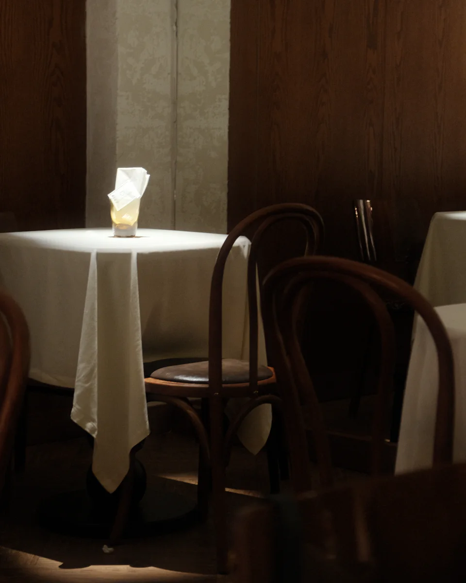 Tables in long white cloths and bentwood chairs in a dim, wood-panelled room